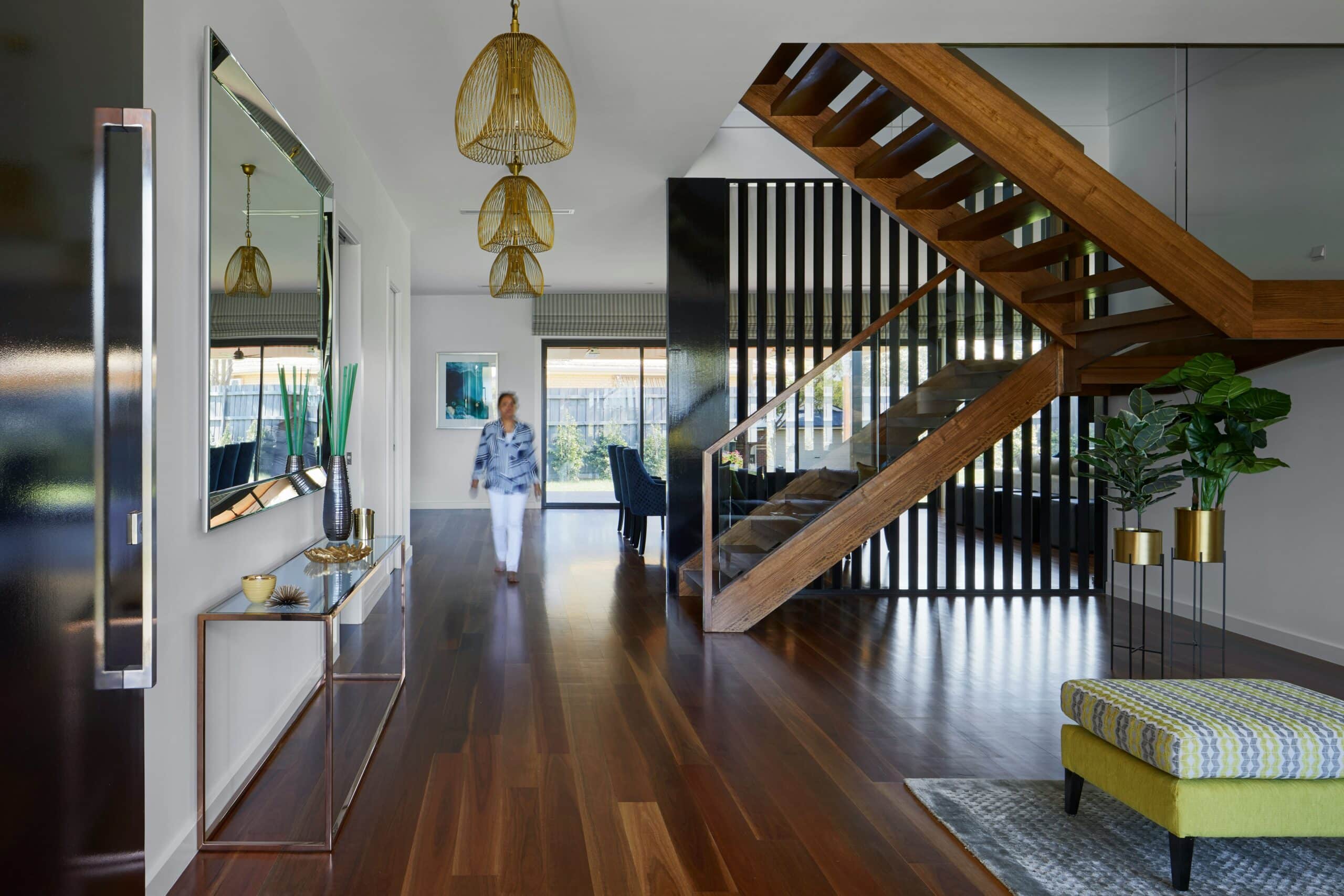 Sala con piso de madera oscuro y un hombre caminando sobre el - Millenium Brokers, pisos e interiorismo